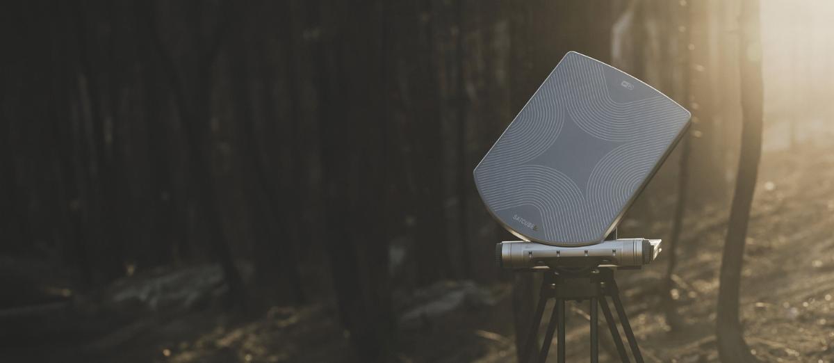 A 1 m drive-away satellite dish deployed on the roof of a parked truck at a remote camp, tents behind