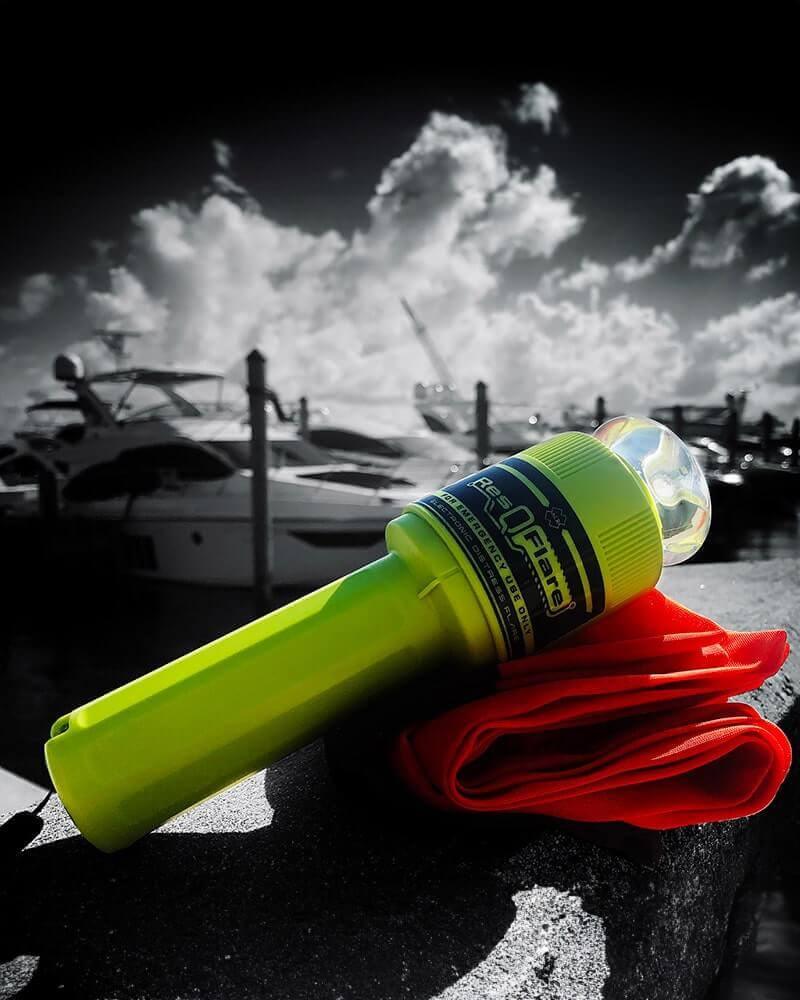 A buoyant personal locator beacon clipped to an inflatable life jacket on the deck of a small boat, spray in the background.