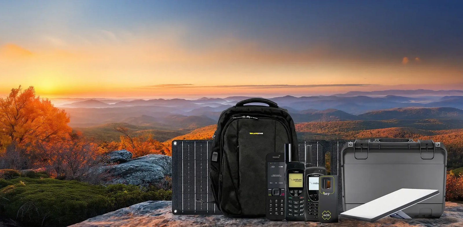 Satellite phone, Starlink terminal, Faraday backpack, solar panel and power station laid out against a mountain sunset