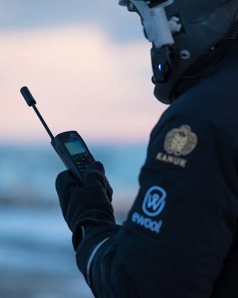 Rescue worker using a satellite phone in cold weather gear