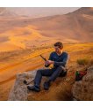 Traveller using an Inmarsat IsatPhone 2 rental on a rock in the desert thumbnail