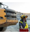 Site worker calling on an Inmarsat IsatPhone 2 rental beside heavy machinery thumbnail